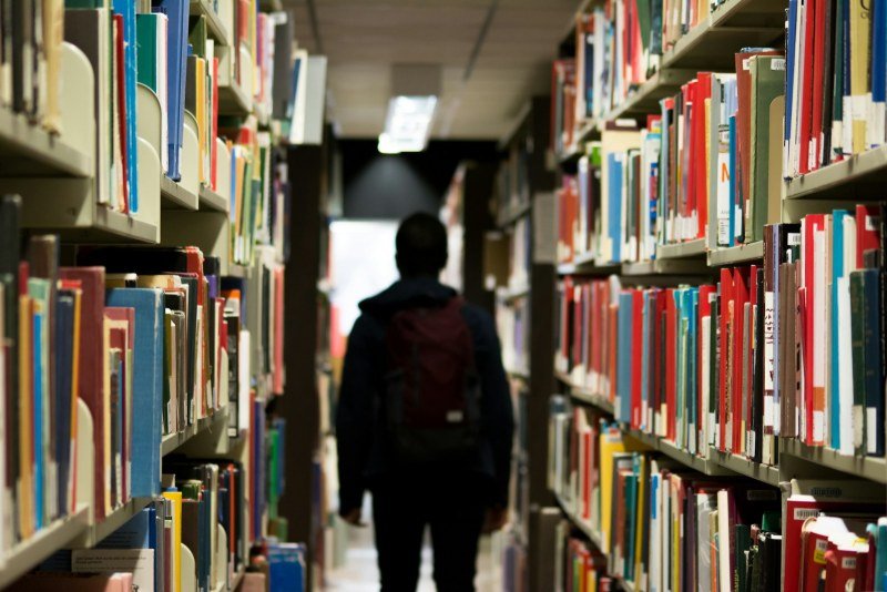 Student walking between shelves in a university library