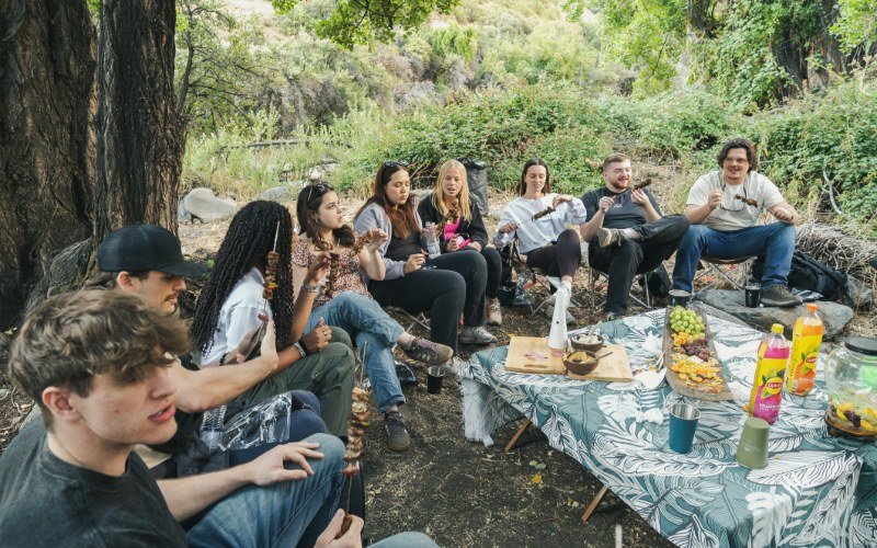 Group sharing lunch in the shade by the river in Yerba Loca