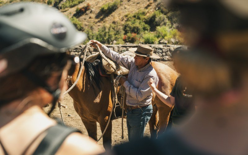 Local huaso adjusting a saddle before the ride in the Andes