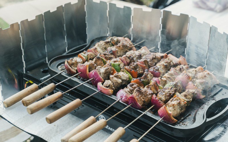 Anticuchos and skewers cooking on a gas grill at a Tour Lab mountain meal in the Andes